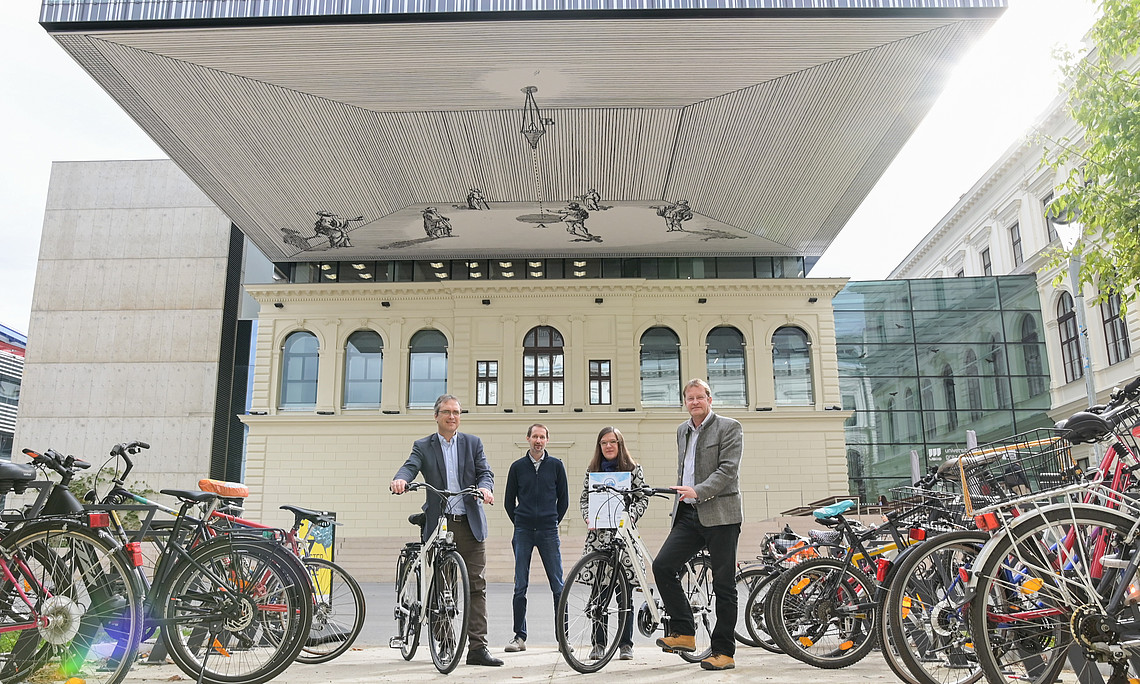 Die Universität Graz hat einiges in Fahrrad-Abstellflächen investiert. Und so wurde sie nach 2017 nun zum zweiten Mal mit der CFE-Zertifizierung zum fahrradfreundlichen Betrieb in "Gold" versehen. Vizerektor Peter Riedler (links) und der Direktor für Ressourcen, Ralph Zettl (rechts), freuen sich über die Auszeichnung. Übergeben wurde die Urkunde von Brigitte Schicho (Fahrradlobby). Foto: Uni Graz/Tzivanopoulos