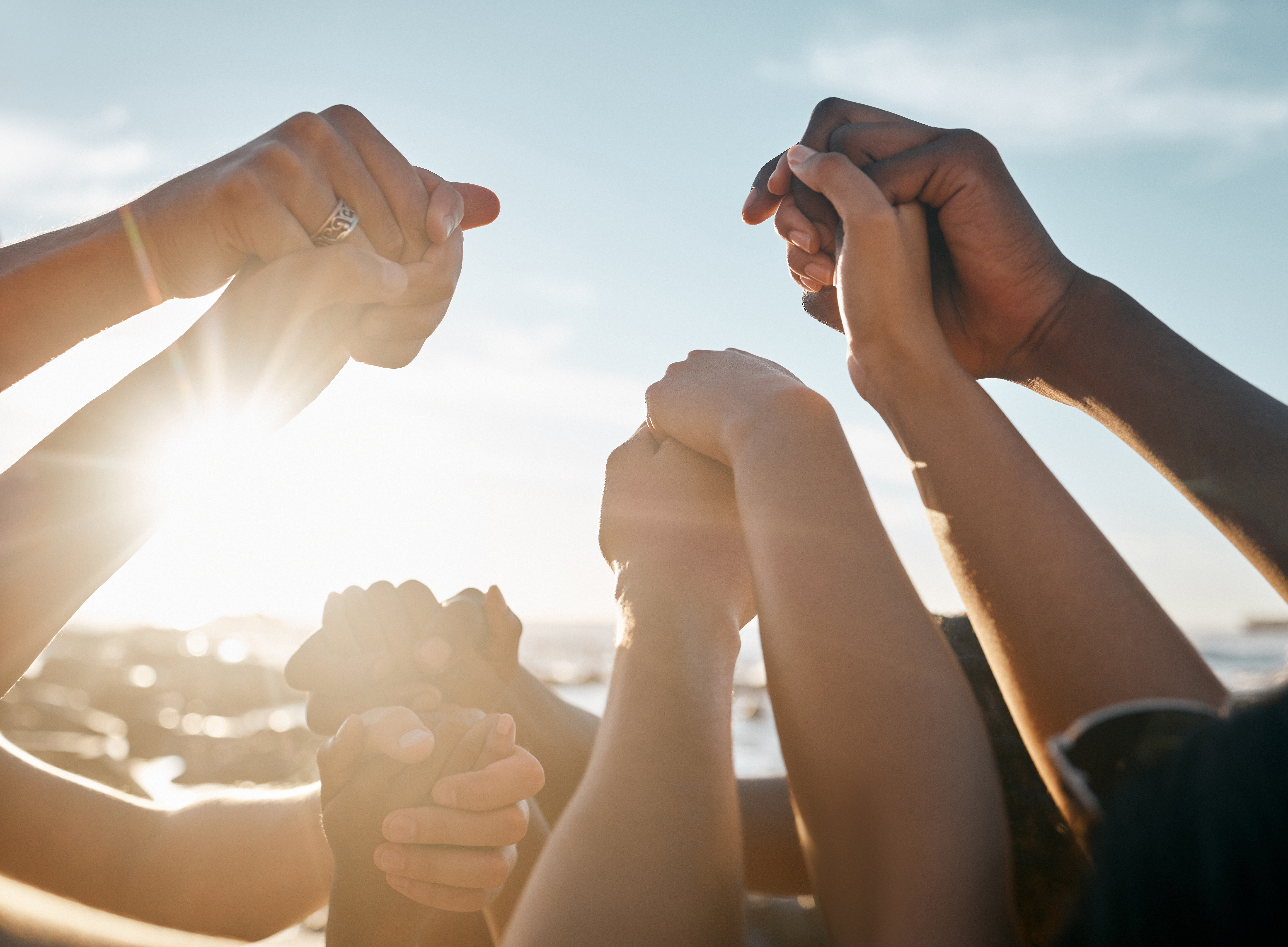 Friends, bonding and holding hands on beach social gathering, community trust support or summer holiday success. Men, women and diversity people in solidarity 