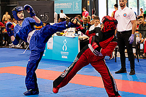 Two kickboxers fighting in the hall, spectators and the referee in the back