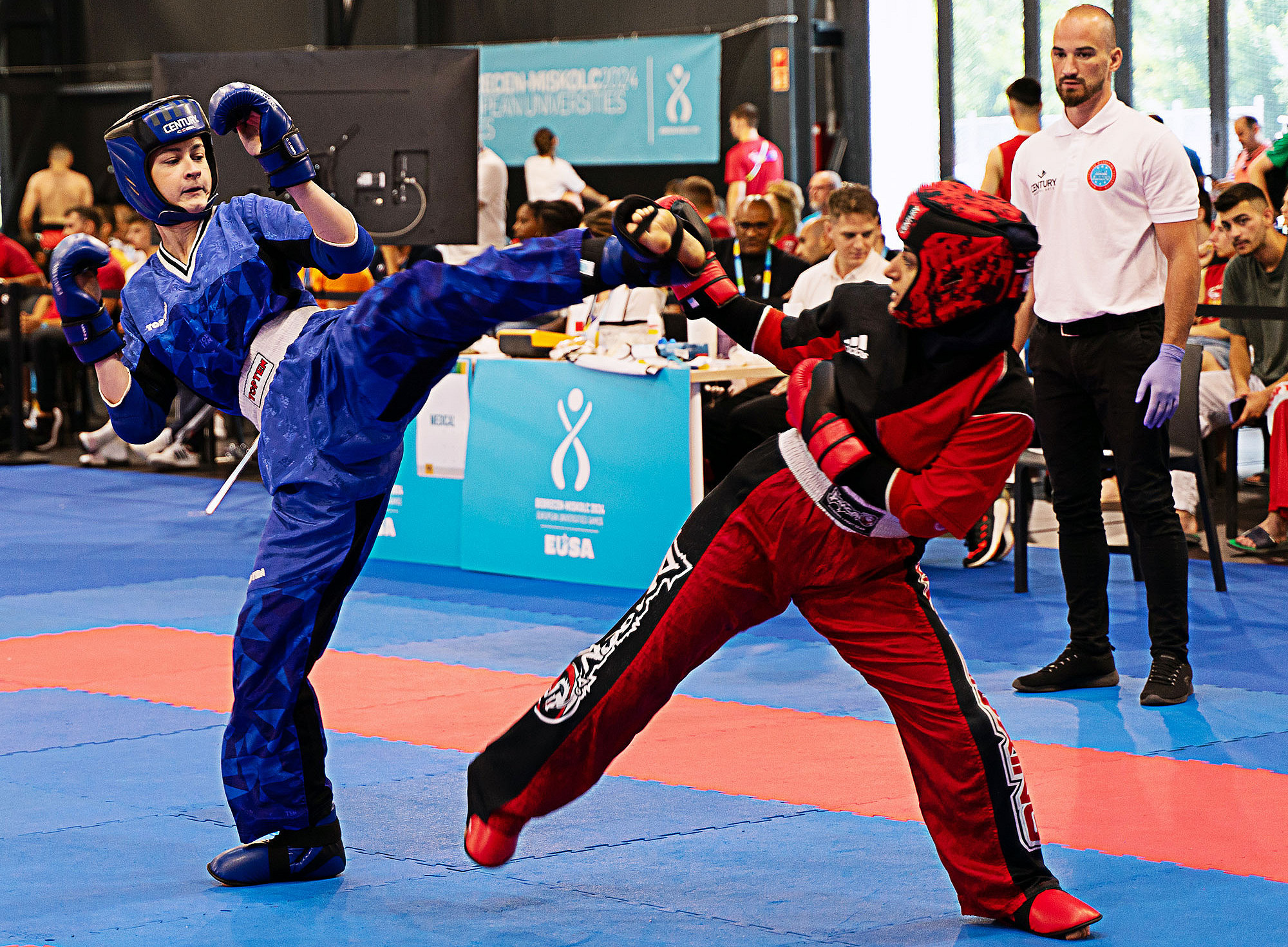 Zwei Kickboxerinnen beim Kämpfen in der Halle, hinten Zusehende und der Schiedsrichter ©Marlene Graßer und Kim Schmidt