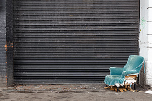 Sanierung von Unternehmen: kaputter Sessel vor geschlossenem Garagentor
