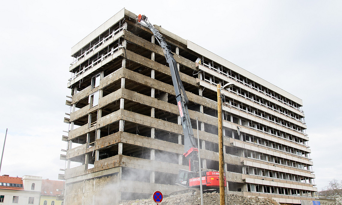 Bagger bricht das Hochhaus ab