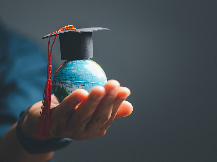 Hand, die kleinen Globus mit Doktorhut hält symbolisiert Internationale und multikulturelle Lehre ©JD8 - stock.adobe.com