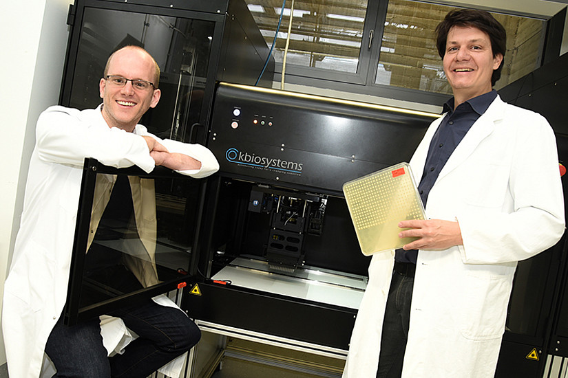 Jonathan Woodsmith (l.) und Ulrich Stelzl (r.) arbeiten mit Bäckerhefe, um große Genbibliotheken mit Hilfe eines Arrayroboters - im Hintergrund - zu durchforsten. 