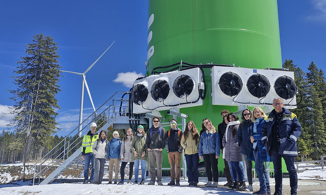 Exkursionsteilnehmer:innen vor dem Fuß der Windkraftanlage