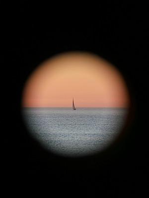 Segelboot am Meer durch ein Teleskop beobachtet 