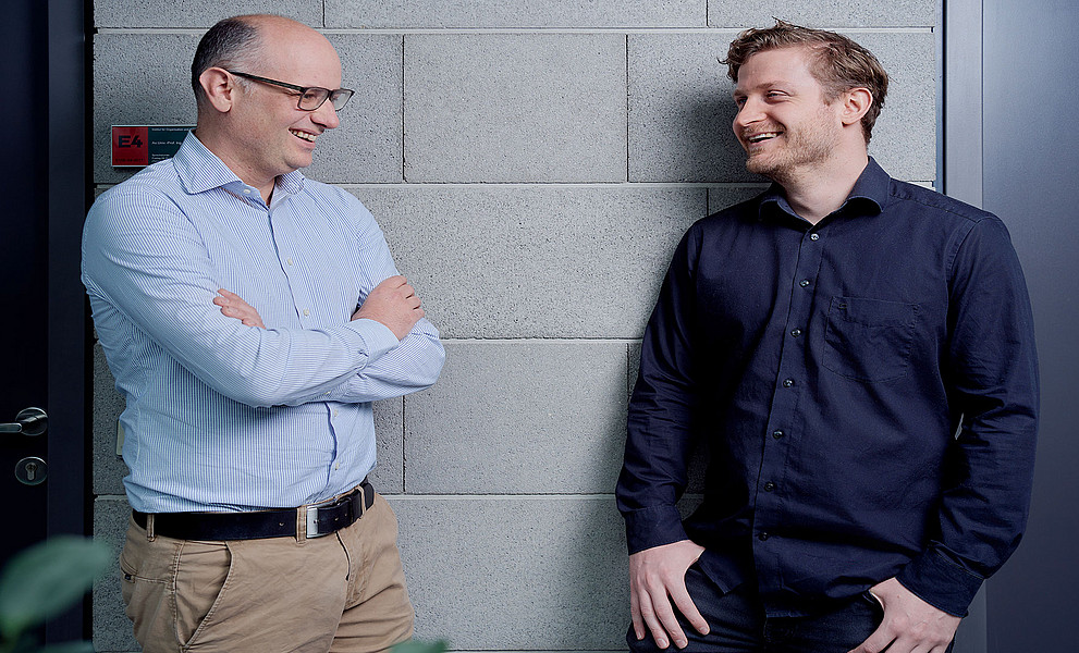 Jürgen Fleiß und Armin Haberl lachend im Gespräch miteinander vor Bürotüren im RESOWI-Zentrum der Uni Graz
