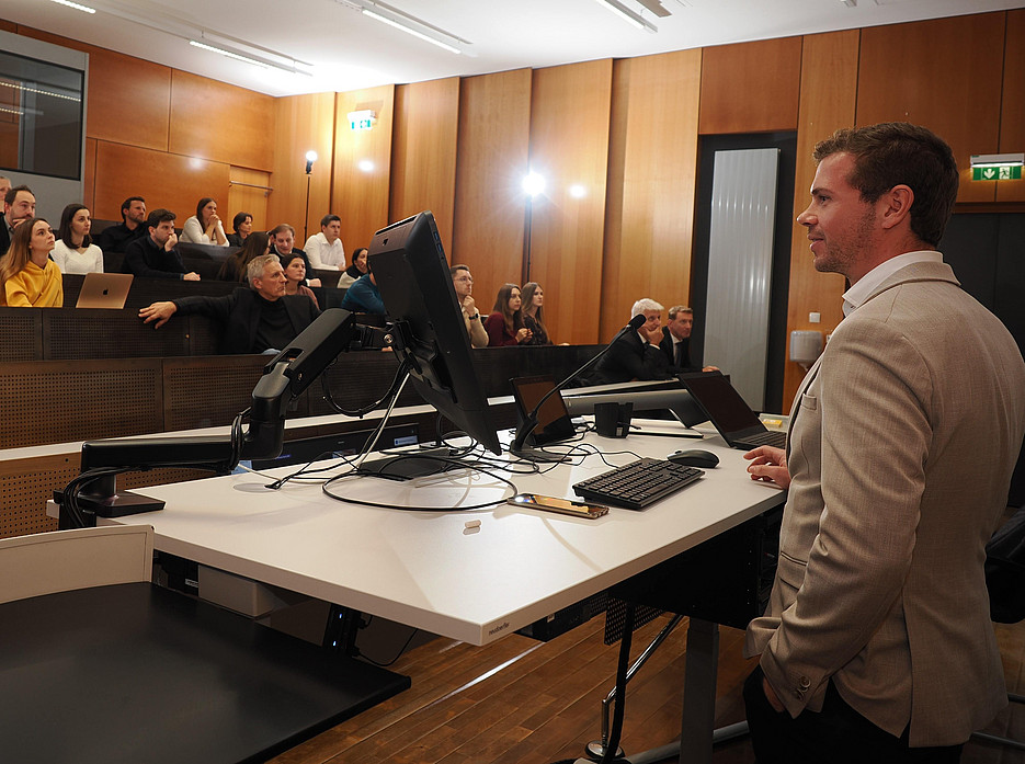 Dr. Johannes Zeiringer steht im Hörsaal ganz vorne beim Computer. Im Hintergrund sieht man das Publikum der Veranstaltung. ©Uni Graz/Mag. Paulus Mayr