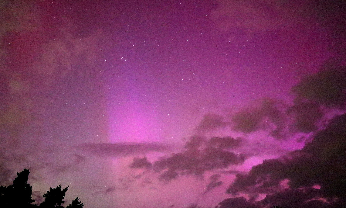 Nachthimmel, leuchtend in bunten Farben mit den Sternen im Hintergrund.