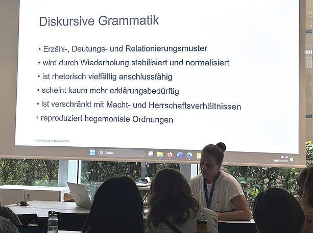 eine Frau sitzt an einem Tisch und hält eine Präsentation, viele Menschen im Publikum hören zu ©Uni Graz/Freidorfer