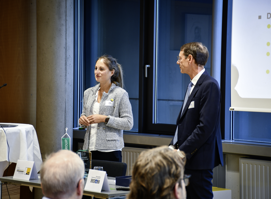 Eine Frau und ein Mann stehen während des Symposiums vor einer Präsentationsleinwand. ©SOWI/Habijanic