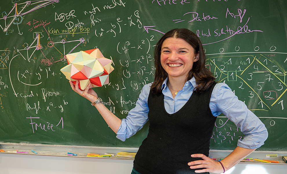 Eine Frau steht vor einer grünen Schultafel