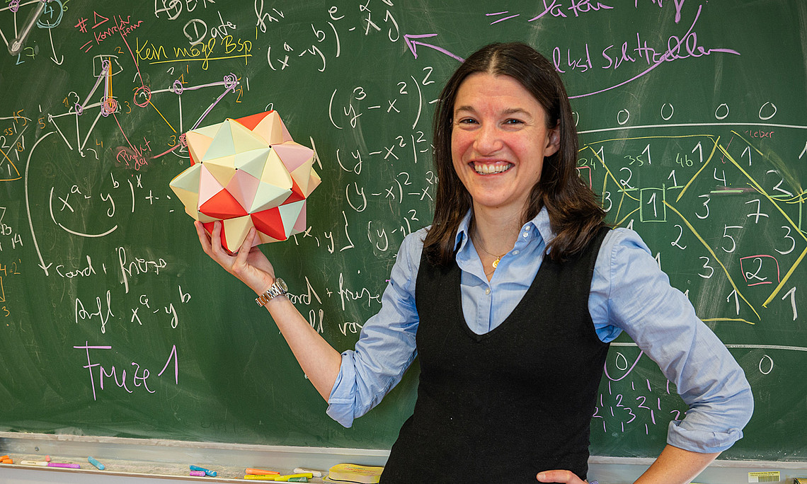 Eine Frau steht vor einer grünen Schultafel