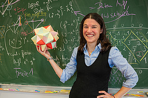 Eine Frau steht vor einer grünen Schultafel