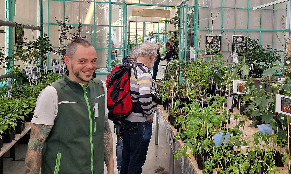 Plant rarities market in the Botanical Garden: two people surrounded by hundreds of vegetable plants in the historic greenhouse.