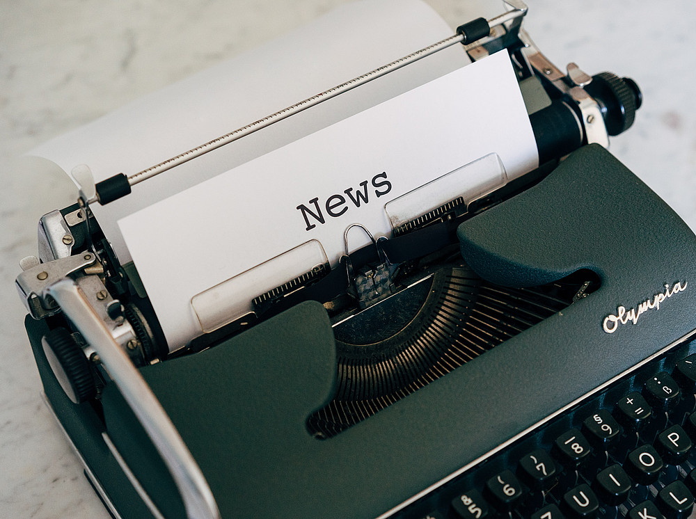 Newsletter Forschungsmanagement und -service, eine grüne Schreibmaschine mit einem weißen Zettel und dem Wort 'News' ©Markus Winkler by unsplash