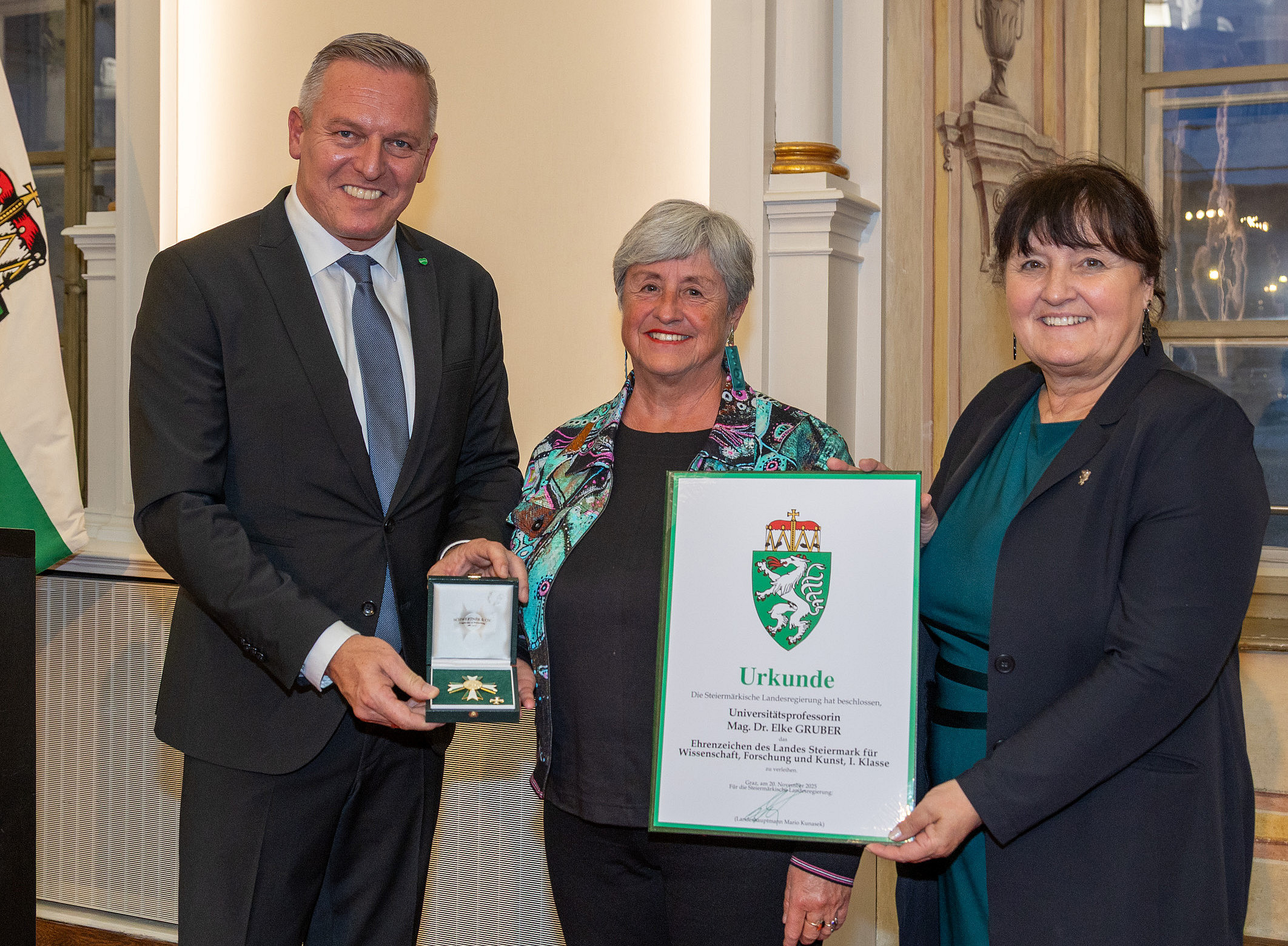 Gruppe (zwei Frauen und ein Mann) von Personen in formeller Kleidung bei einer Auszeichnungen in einem festlichen Raum. ©Fotoatelier Robert Frankl