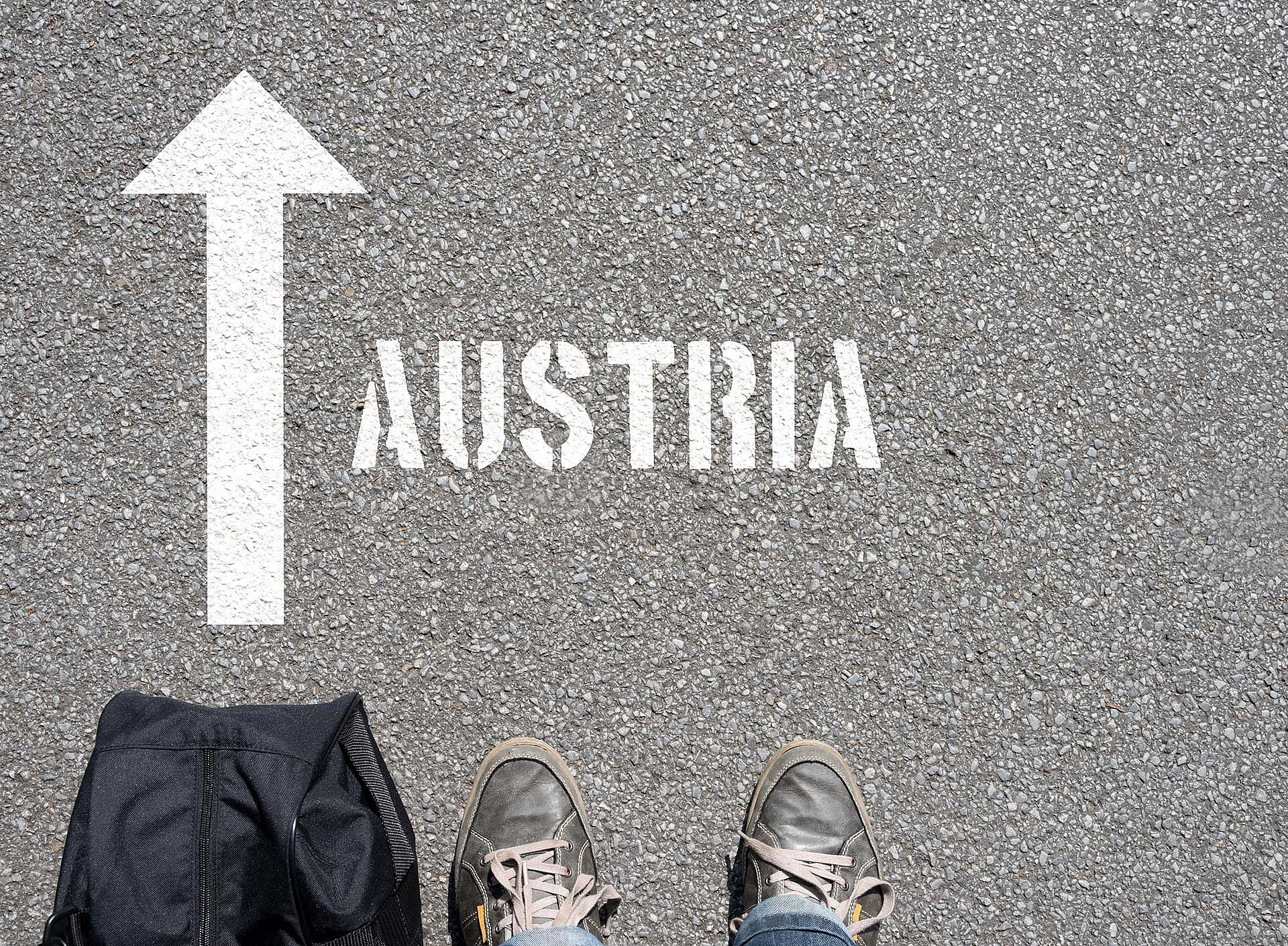 Füße vor Pfeil auf Asphalt mit Schrift Austria 
