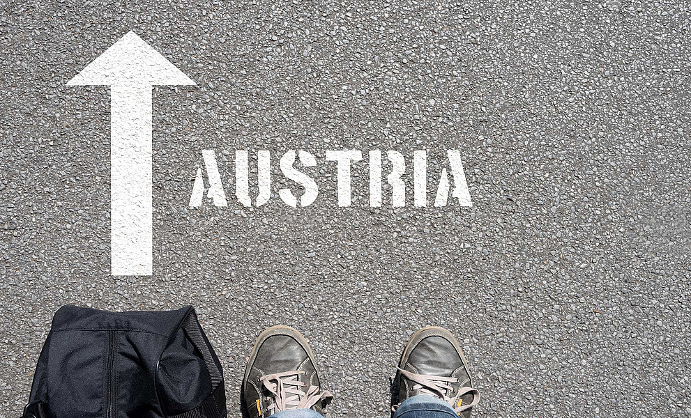 Füße vor Pfeil auf Asphalt mit Schrift Austria