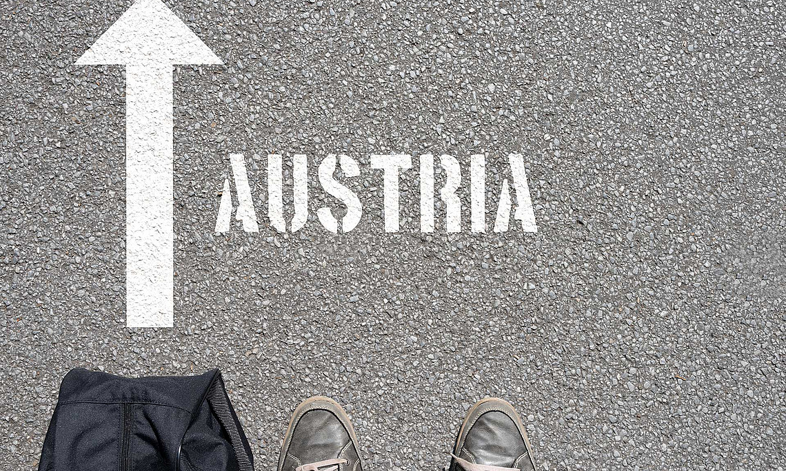 Füße vor Pfeil auf Asphalt mit Schrift Austria
