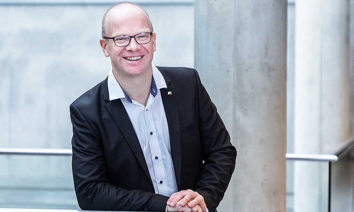 Stefan Thalmann stützt sich auf ein Geländer und schaut sehr freundlich
