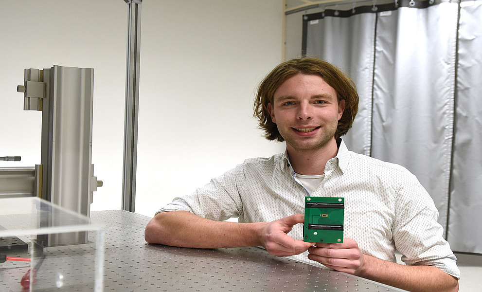Johannes Bütow im Labor mit dem neuartigen Chip in der Hand