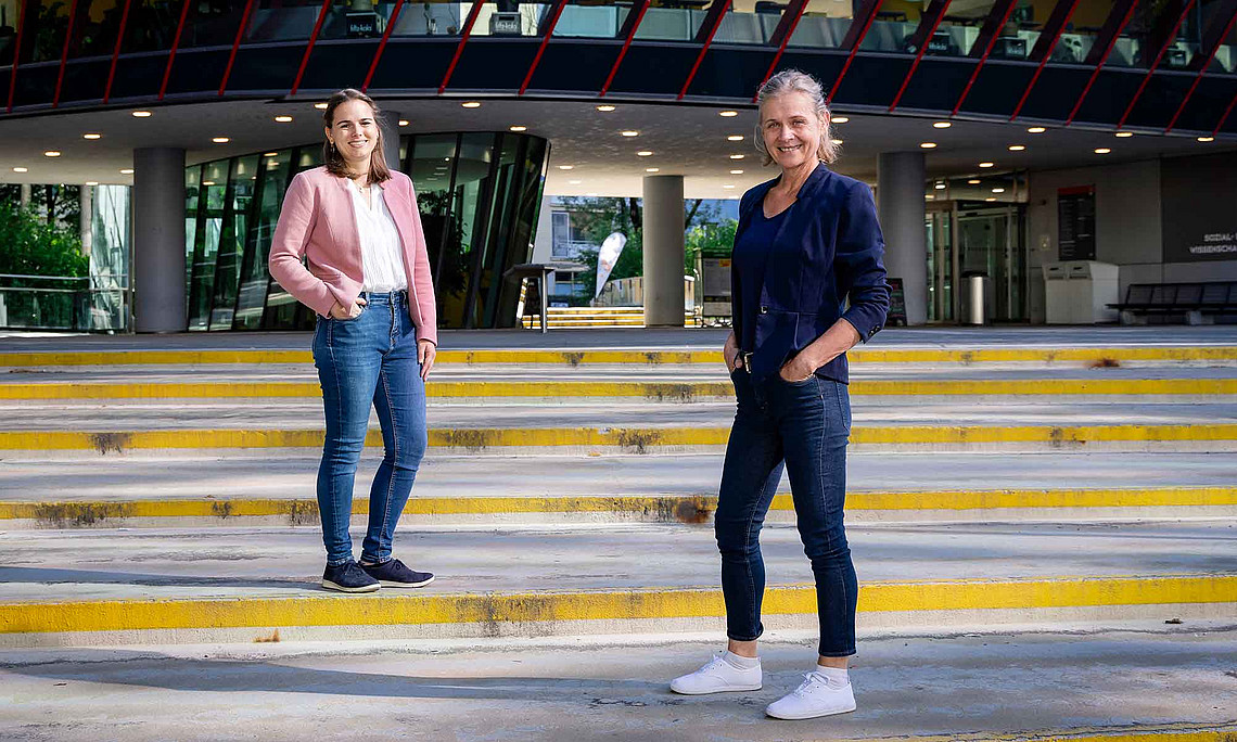 Zwei Frauen stehen auf Stufen vor einem Gebäude
