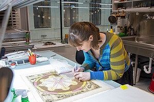 A woman is restoring a book. 