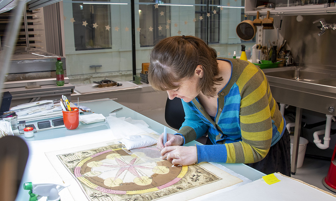 A woman is restoring a book. 