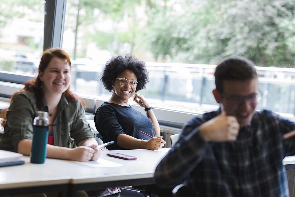 Studierende sitzen in Seminarraum und lachen gemeinsam