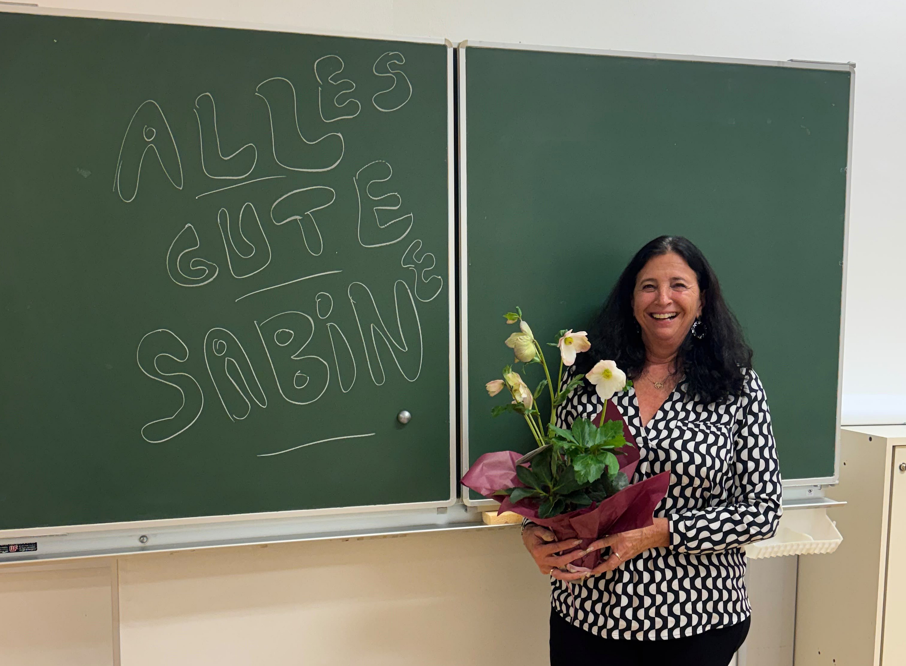 eine Frau steht mit Blumen vor einer Tafel ©Uni Graz/Seiser