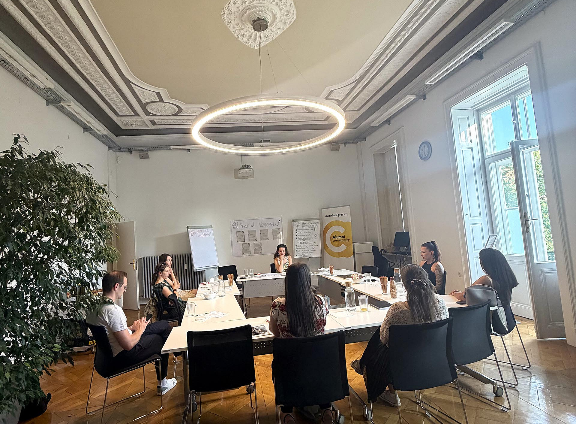 Personen die an zu einem Quadrat zusammengestellten Tisch sitzen ©Michaela Wright