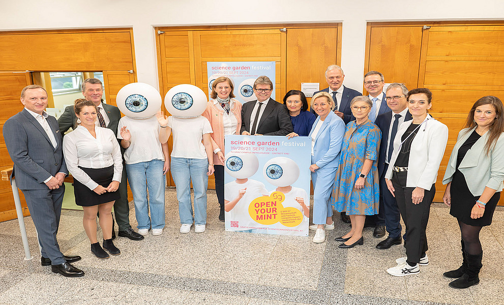Gruppenfoto mit Vertreter:innen der Hochschulen, Industriellenvereinigung und Politik mit Maskottchen