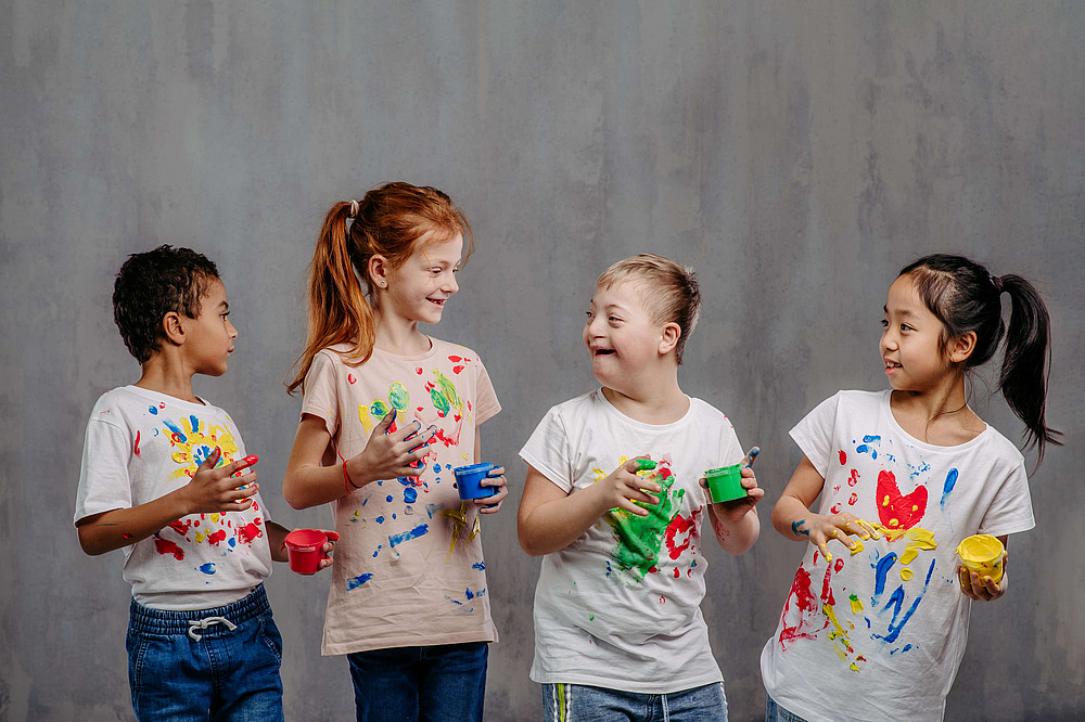 lachende Kinder mit bemalten T-Shirts symbolisieren das Forschungsprojekt Implement ICF ©stock.adobe.com/Halfpoint