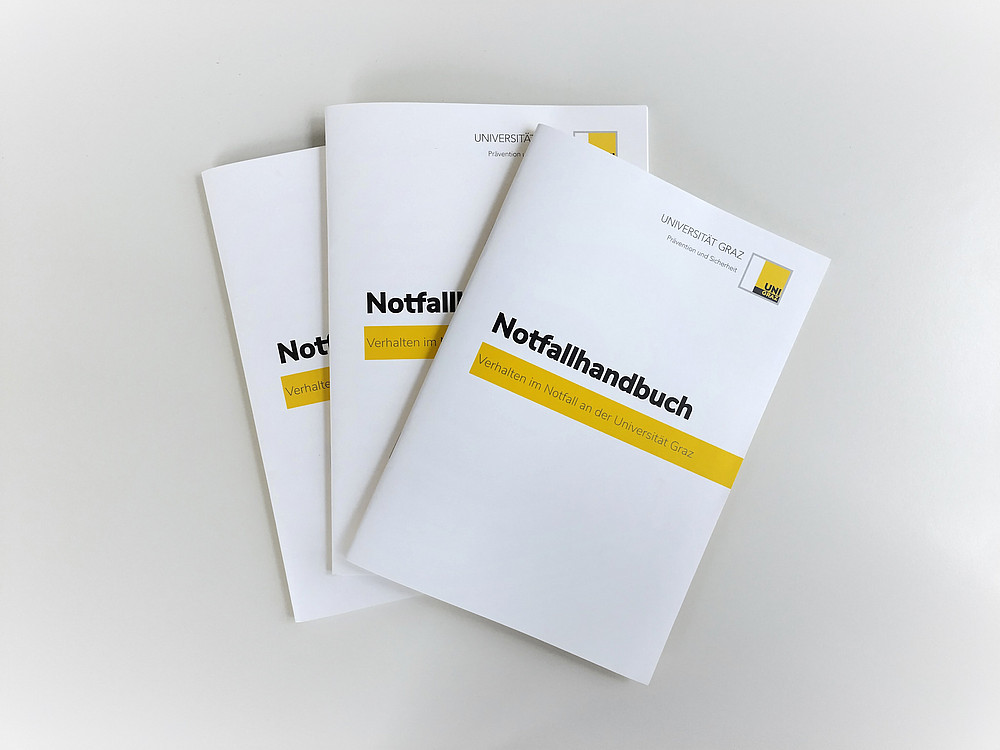 Drei Notfallhandbücher liegen übereinander auf einer Fläche ©Universität Graz