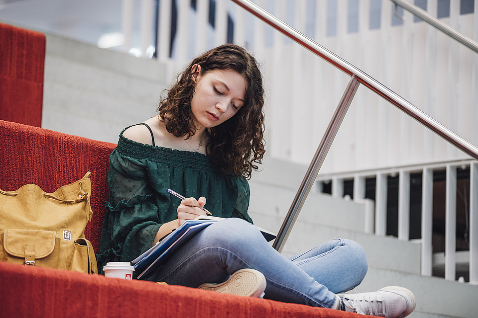 Eine Studierende lernt auf der Universitätsbibliotheks-Treppe