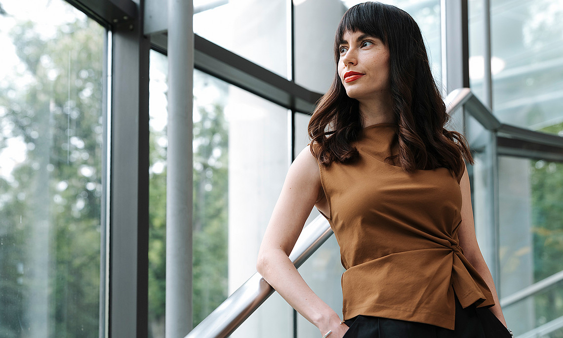 Sociologist Zorica Sirocic leans against a banister and looks to her left into the distance.