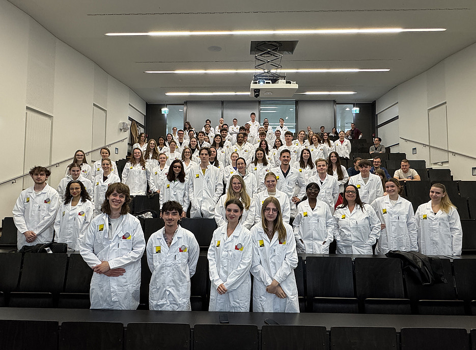 Studierende mit Labormantel im Hörsaal 