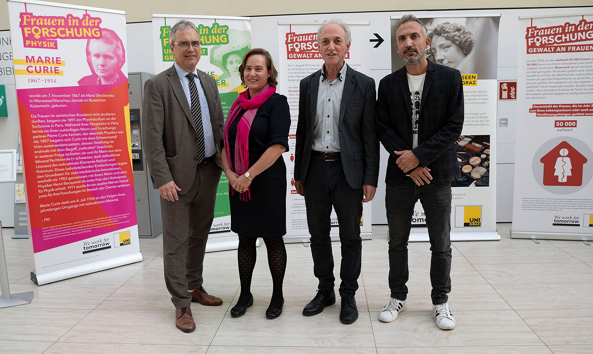 Four people – three men and one woman – are standing in front of a wall of posters. ©Uni Graz/Leljak