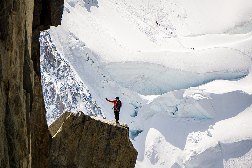 Wanderer auf Felswand mit Ausblick auf Gletscher: Mut zur Veränderung heißt Mut zum Leben