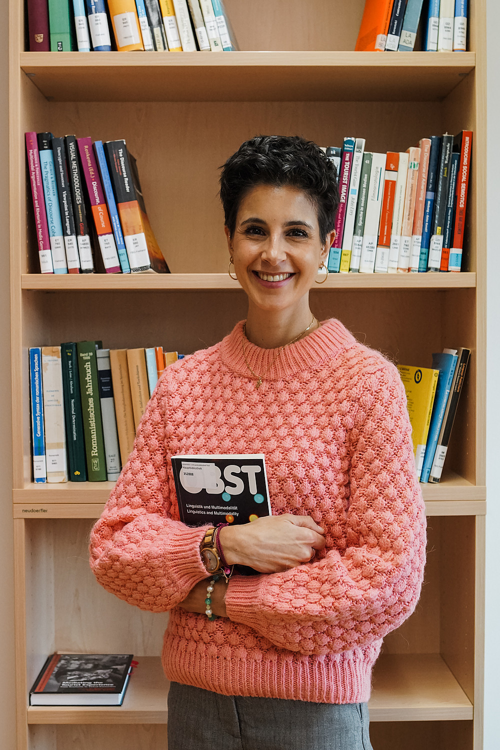 Person mit Buch in der Hand vor Bücherregal 