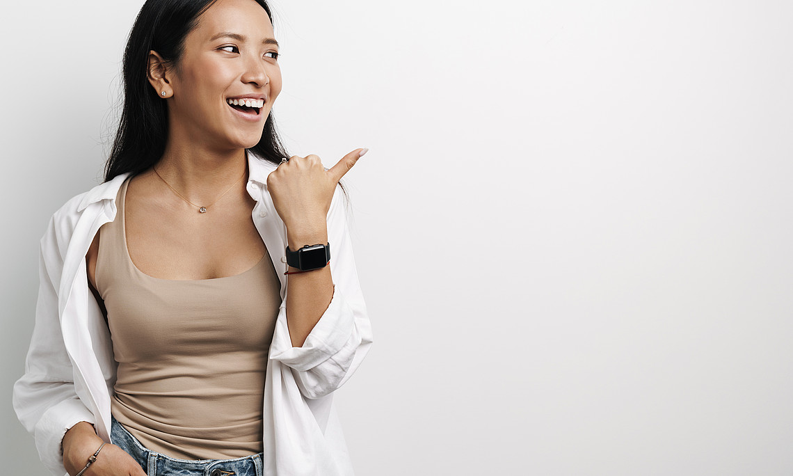 Beautiful Happy Asian Woman Laughing and Pointing Finger Aside
