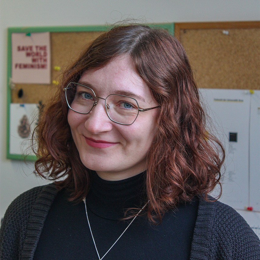Portraitfoto einer Frau mit schulterlangen lockigen Haaren und einer Brille