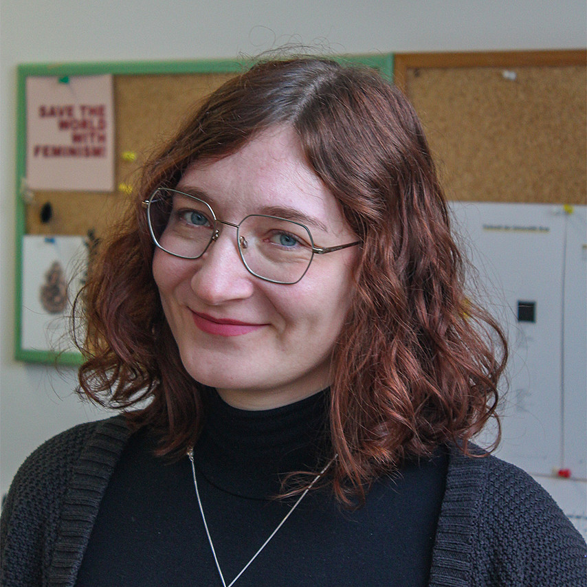 Portraitfoto einer Frau mit schulterlangen lockigen Haaren und einer Brille