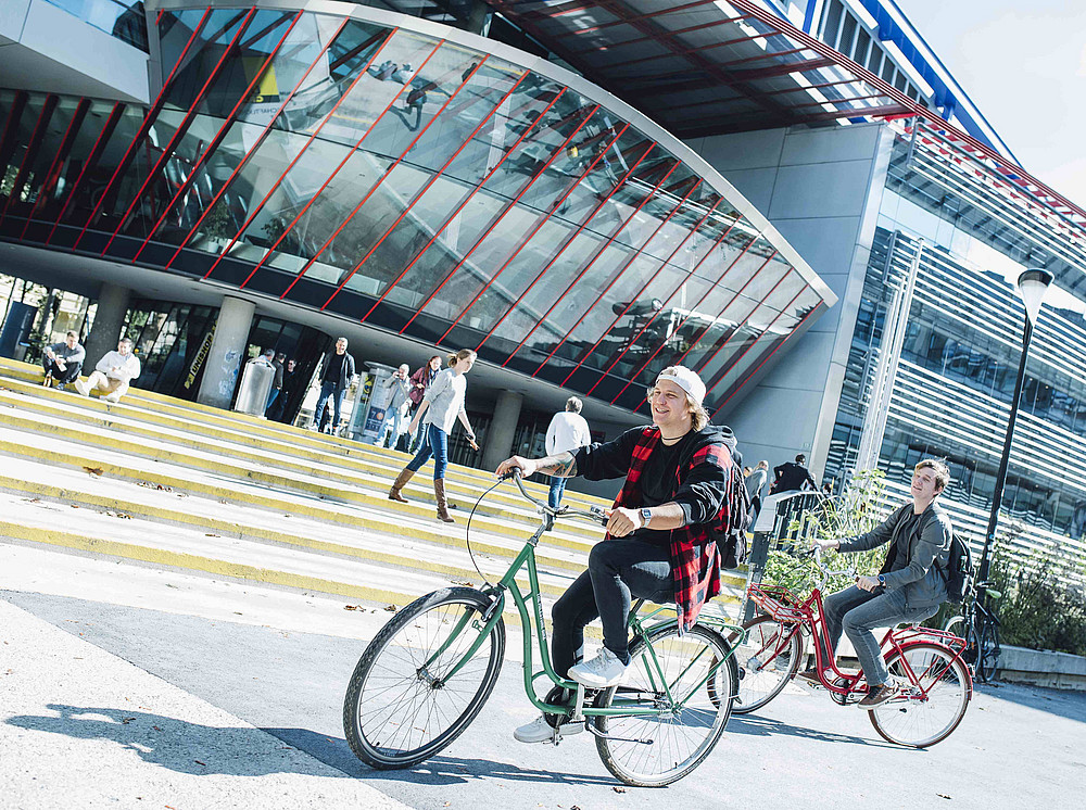 Two young men on bicycles in front of the RESOWI building, subject image Study Department at the University of Graz ©Uni Graz/Kanizaj