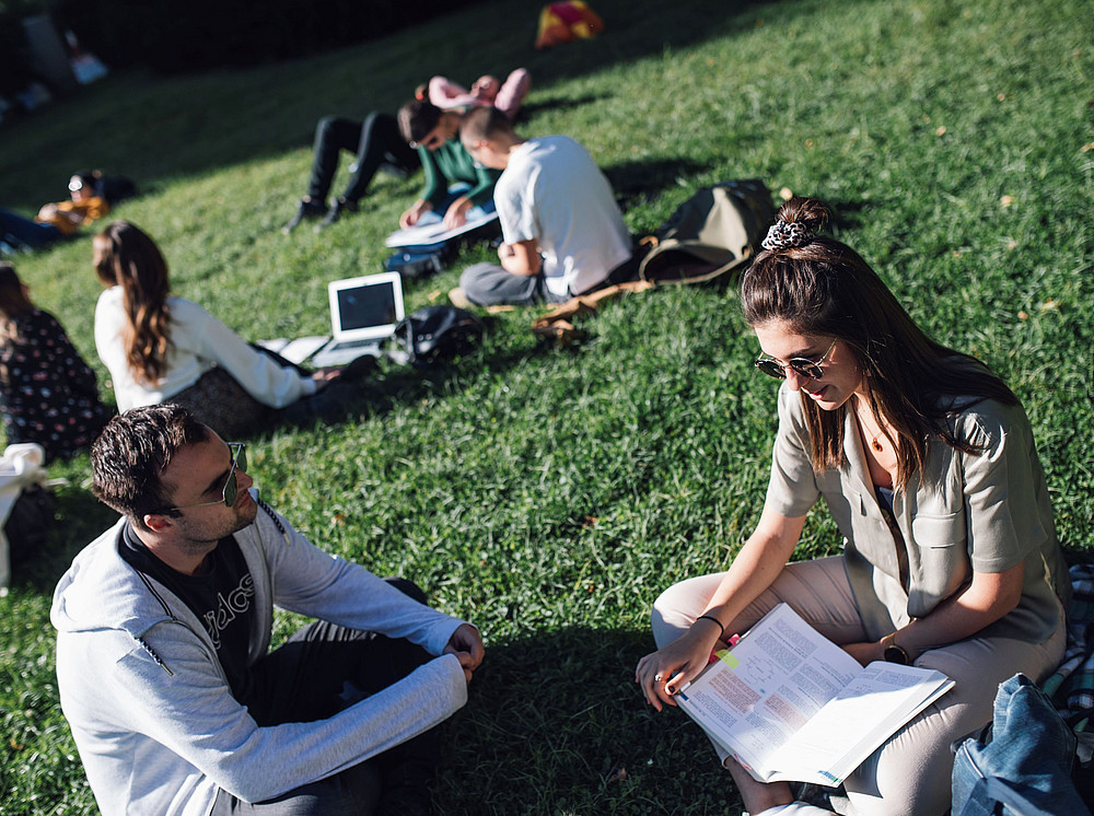 Zwei Studierende sitzen auf der Wiese am Campus und lernen gemeinsam. ©Uni Graz/Kanizaj