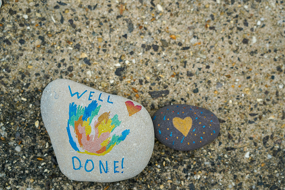 Steine auf Strand; auf einem steht "well done" am andern ist ein Herz ©Nick Fewings auf Unsplash 