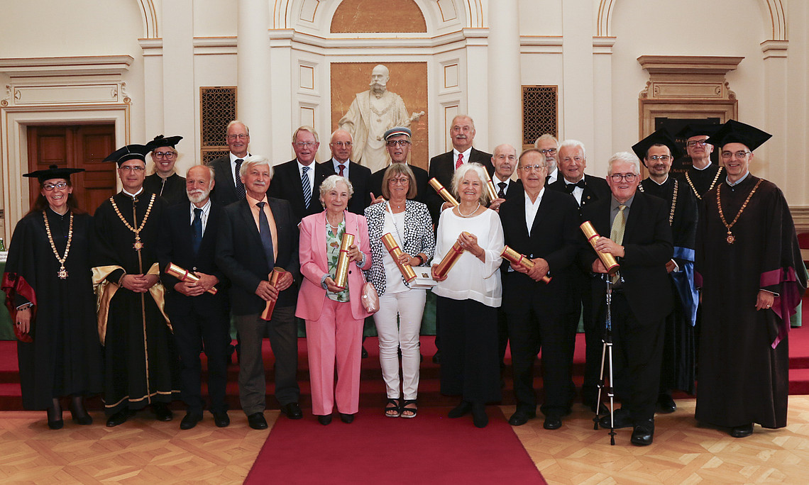 Die 15 geehrten Absolvent:innen mit ihren goldenen Urkunden