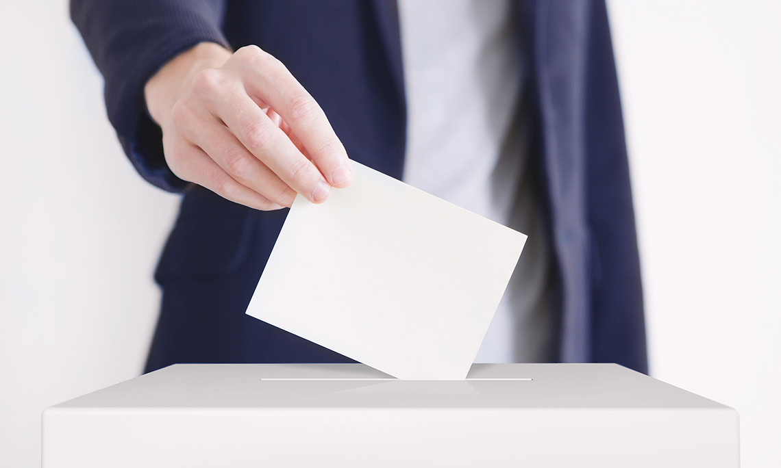 man putting a ballot into a voting box