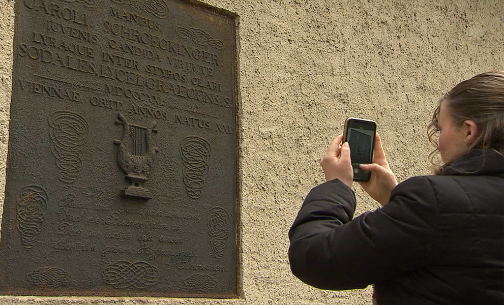 Schülerin fotografiert mit dem Handy eine Inschrift